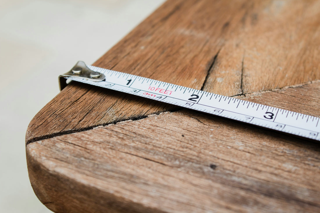 Measuring living room space with tape measure before buying furniture online